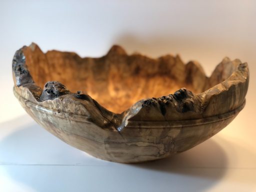 Wooden bowl with a rough, natural edge and smooth, polished interior.
